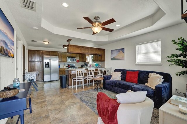 living area featuring a tray ceiling, recessed lighting, visible vents, and a ceiling fan