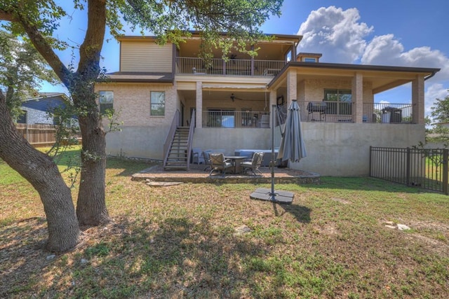 back of house with brick siding, a yard, stairway, fence, and a balcony