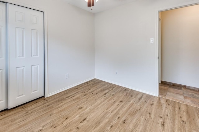 unfurnished bedroom featuring ceiling fan, light wood-type flooring, and a closet