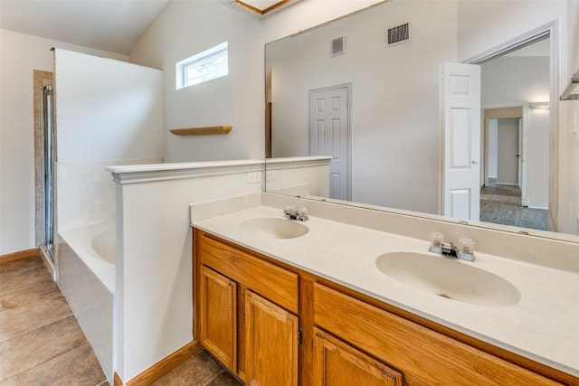 bathroom with a relaxing tiled tub, lofted ceiling, tile patterned floors, and dual bowl vanity