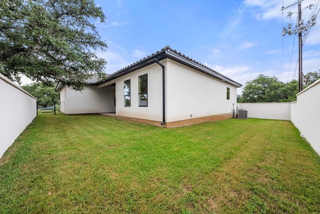 rear view of house featuring central air condition unit and a lawn