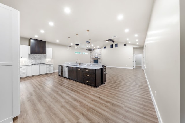 kitchen featuring lofted ceiling, wall chimney exhaust hood, dark brown cabinetry, white cabinetry, and hanging light fixtures