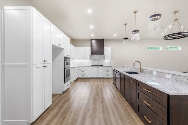 kitchen with extractor fan, decorative light fixtures, tasteful backsplash, sink, and white cabinets