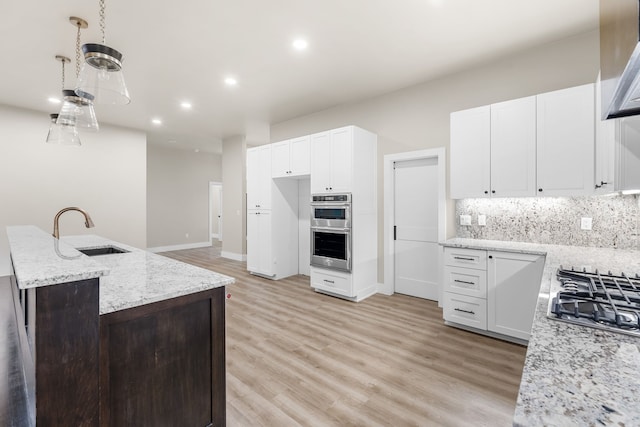 kitchen featuring sink, stainless steel appliances, white cabinets, and light stone countertops