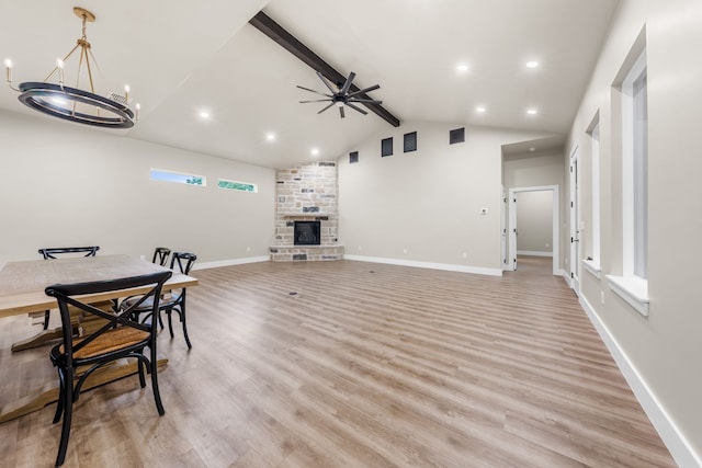 living room with lofted ceiling with beams, ceiling fan with notable chandelier, a fireplace, and light hardwood / wood-style floors