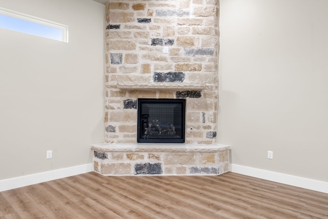 interior details featuring wood-type flooring and a stone fireplace