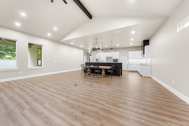 dining space with beamed ceiling, plenty of natural light, and light wood-type flooring