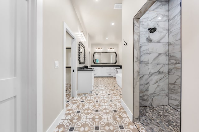 bathroom featuring vanity, a tile shower, and tile patterned floors