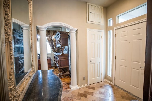 foyer with decorative columns and a healthy amount of sunlight