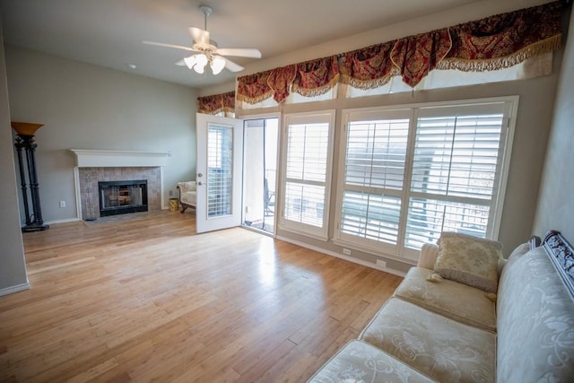 living room featuring a tiled fireplace, light hardwood / wood-style flooring, and ceiling fan