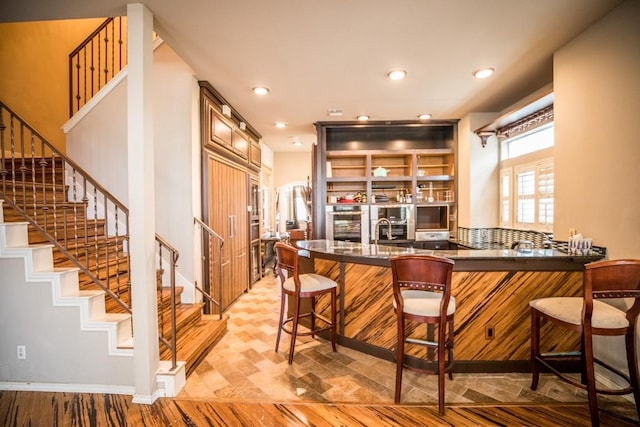 kitchen featuring sink, a breakfast bar area, light hardwood / wood-style floors, and kitchen peninsula