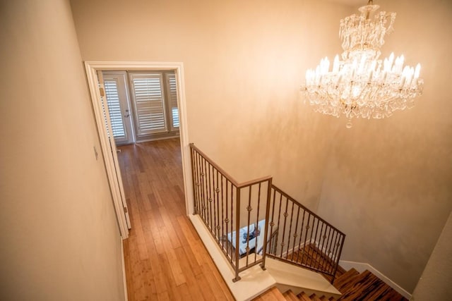 staircase with hardwood / wood-style floors and a notable chandelier