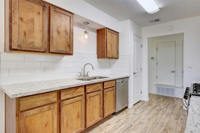 kitchen featuring sink, appliances with stainless steel finishes, hanging light fixtures, light stone countertops, and light wood-type flooring