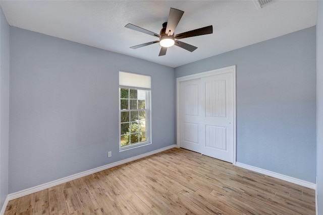 unfurnished bedroom featuring ceiling fan, a closet, and light wood-type flooring