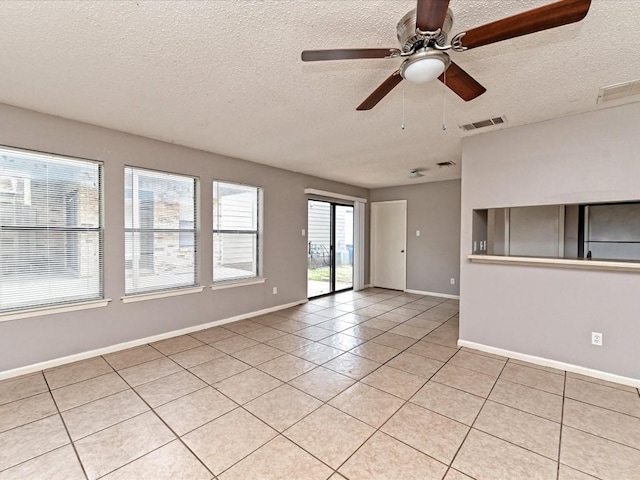 tiled empty room with ceiling fan and a textured ceiling