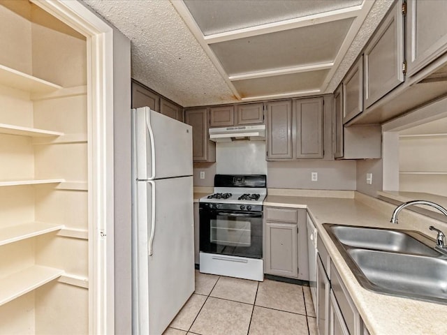 kitchen with range with gas stovetop, sink, white fridge, and light tile patterned floors