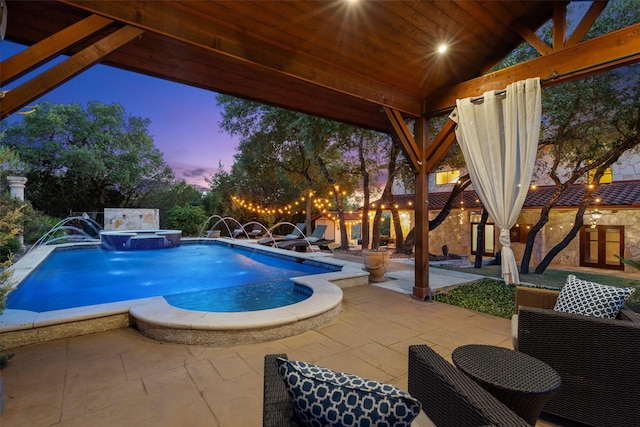 pool at dusk featuring an in ground hot tub, a patio, and pool water feature