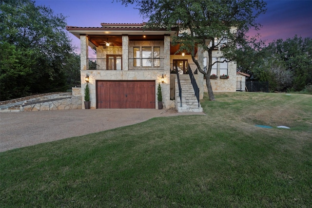 view of front facade featuring a balcony, a garage, and a lawn