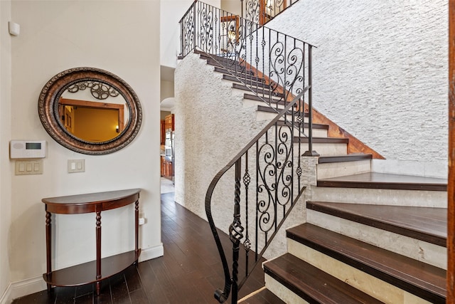 stairway featuring a towering ceiling and wood-type flooring