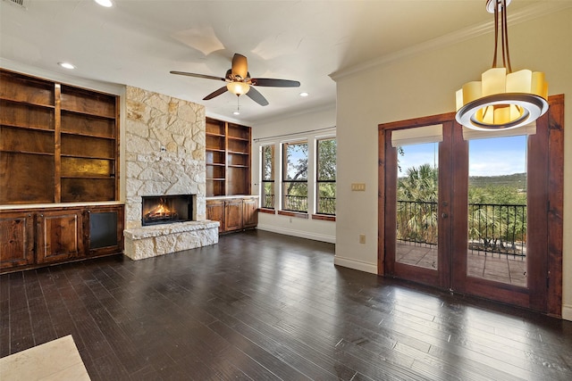 unfurnished living room featuring built in features, dark hardwood / wood-style flooring, ornamental molding, and a fireplace