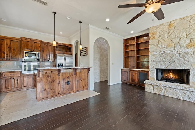 201 Cowal Dr N, Spicewood, TX 78669 - kitchen with appliances with stainless steel finishes, arched walkways, ornamental molding, open floor plan, and a fireplace