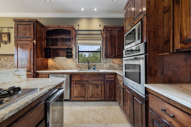 kitchen featuring stainless steel appliances, sink, light stone counters, light tile patterned floors, and crown molding