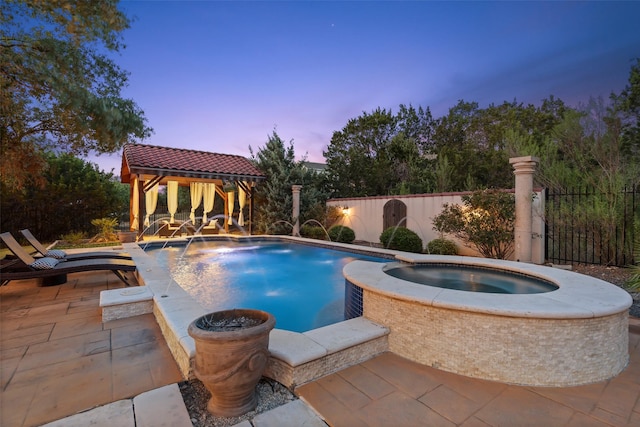 pool at dusk featuring pool water feature, an in ground hot tub, a patio area, and a gazebo