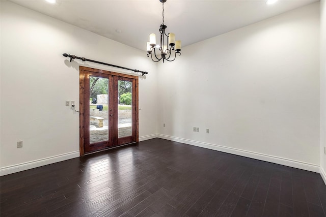 spare room featuring dark hardwood / wood-style floors, french doors, and an inviting chandelier