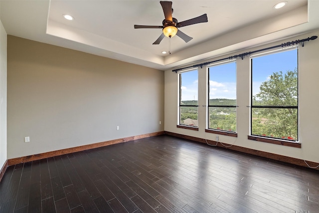 unfurnished room featuring dark wood-type flooring, ceiling fan, and a raised ceiling