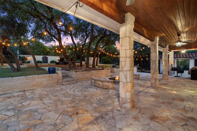 patio terrace at dusk featuring a fire pit and area for grilling