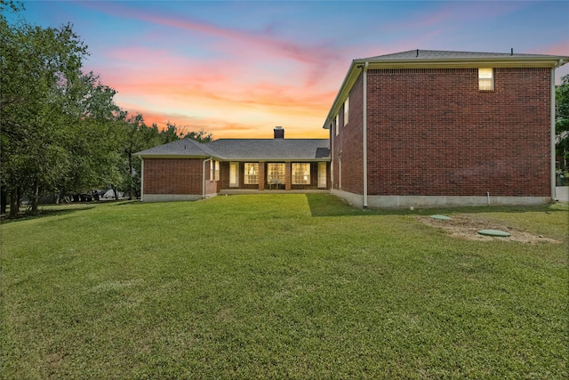 back house at dusk with a lawn