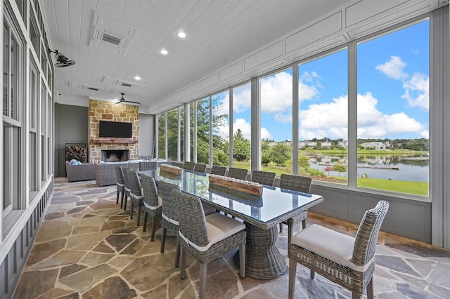 sunroom / solarium featuring wooden ceiling and a stone fireplace