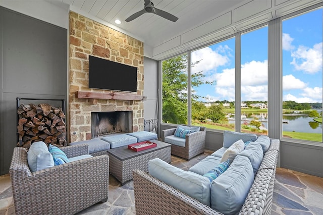 sunroom / solarium with ceiling fan and an outdoor stone fireplace