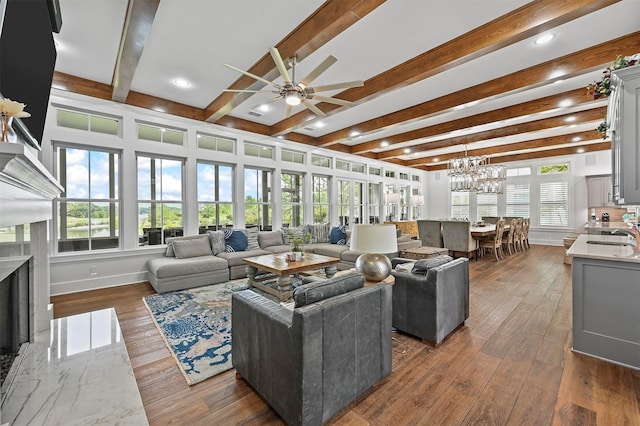 living room with ceiling fan with notable chandelier, a premium fireplace, sink, dark hardwood / wood-style floors, and beam ceiling