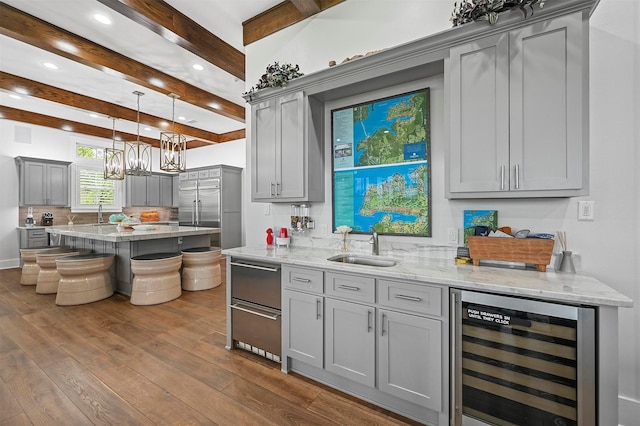 kitchen with decorative light fixtures, beam ceiling, sink, gray cabinetry, and beverage cooler