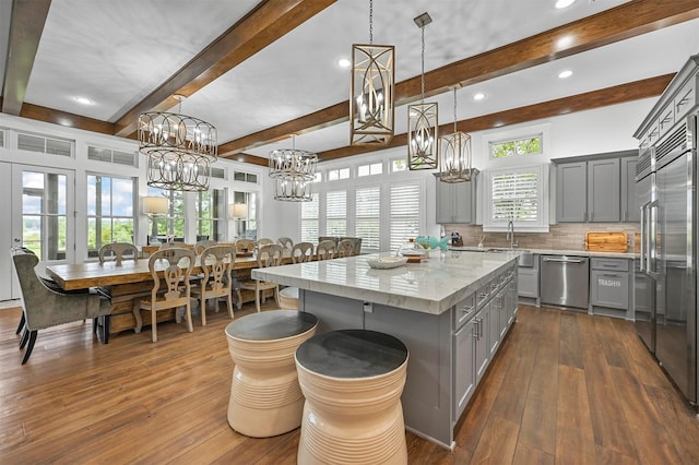 kitchen with a kitchen island, stainless steel appliances, backsplash, hanging light fixtures, and gray cabinetry