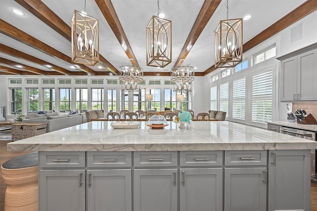 kitchen with light stone counters, pendant lighting, gray cabinetry, and a kitchen island