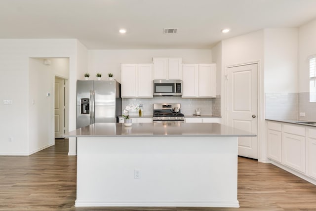 kitchen featuring backsplash, white cabinetry, a center island, and stainless steel appliances