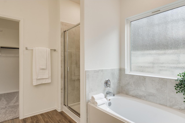 bathroom with hardwood / wood-style flooring and shower with separate bathtub