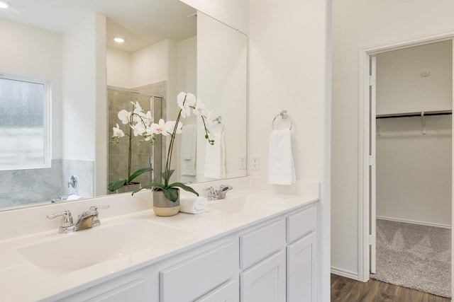 bathroom with hardwood / wood-style flooring, walk in shower, and vanity