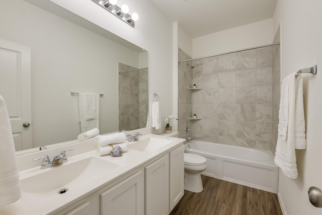 full bathroom featuring tiled shower / bath combo, hardwood / wood-style flooring, toilet, and vanity