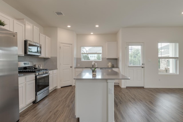 kitchen with a kitchen island, white cabinets, light wood-type flooring, and appliances with stainless steel finishes