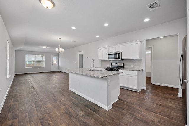 kitchen featuring a kitchen island with sink, stainless steel appliances, light stone countertops, sink, and white cabinets