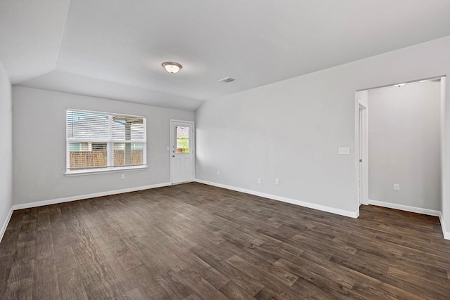 empty room with dark wood-type flooring and lofted ceiling