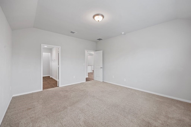 unfurnished bedroom with carpet floors, a spacious closet, and lofted ceiling