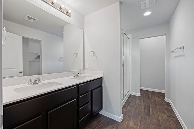 bathroom featuring wood-type flooring, a shower with shower door, and vanity