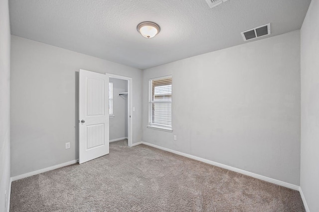 spare room with a textured ceiling and light colored carpet