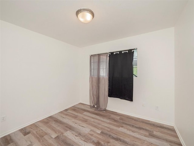 unfurnished room with baseboards and light wood-style flooring