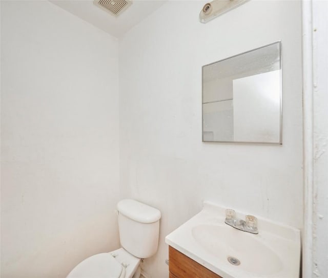 half bath featuring vanity, toilet, and visible vents