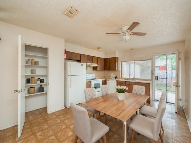 dining space with sink, a textured ceiling, ceiling fan, and light parquet flooring